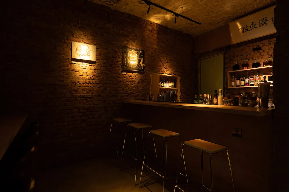昏暗的餐酒吧內有磚牆、工業風燈具和木製吧台。