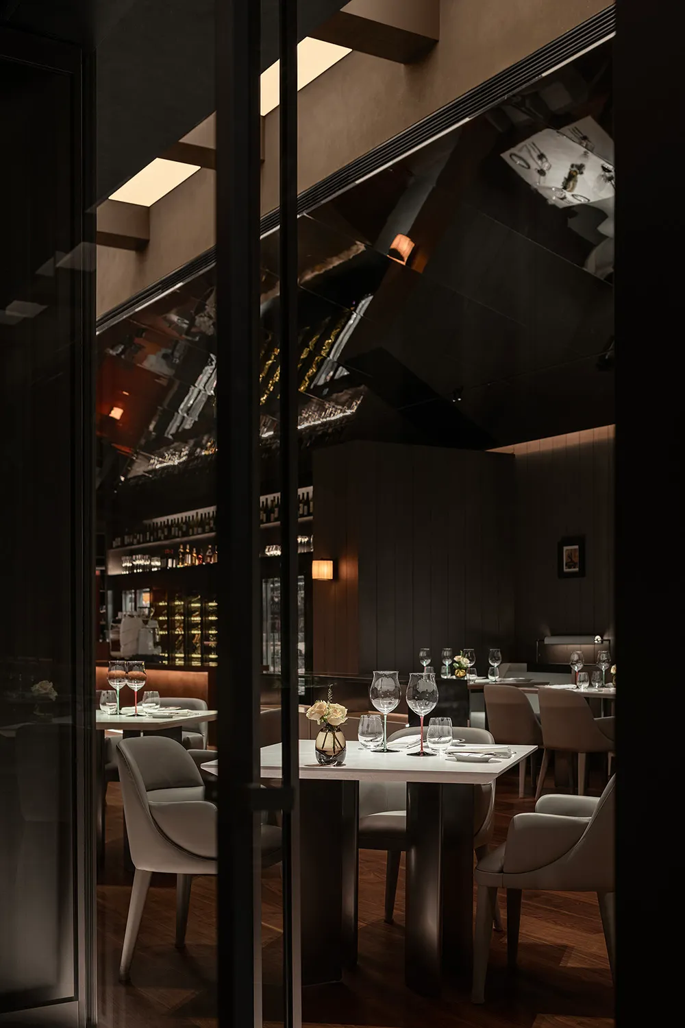 Modern restaurant interior with glass walls and tables.