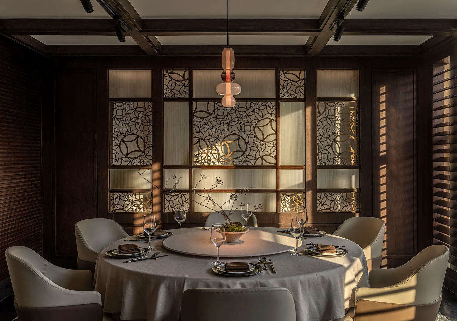 Modern dining room featuring a round table with glass drinkware and a central decorative plant