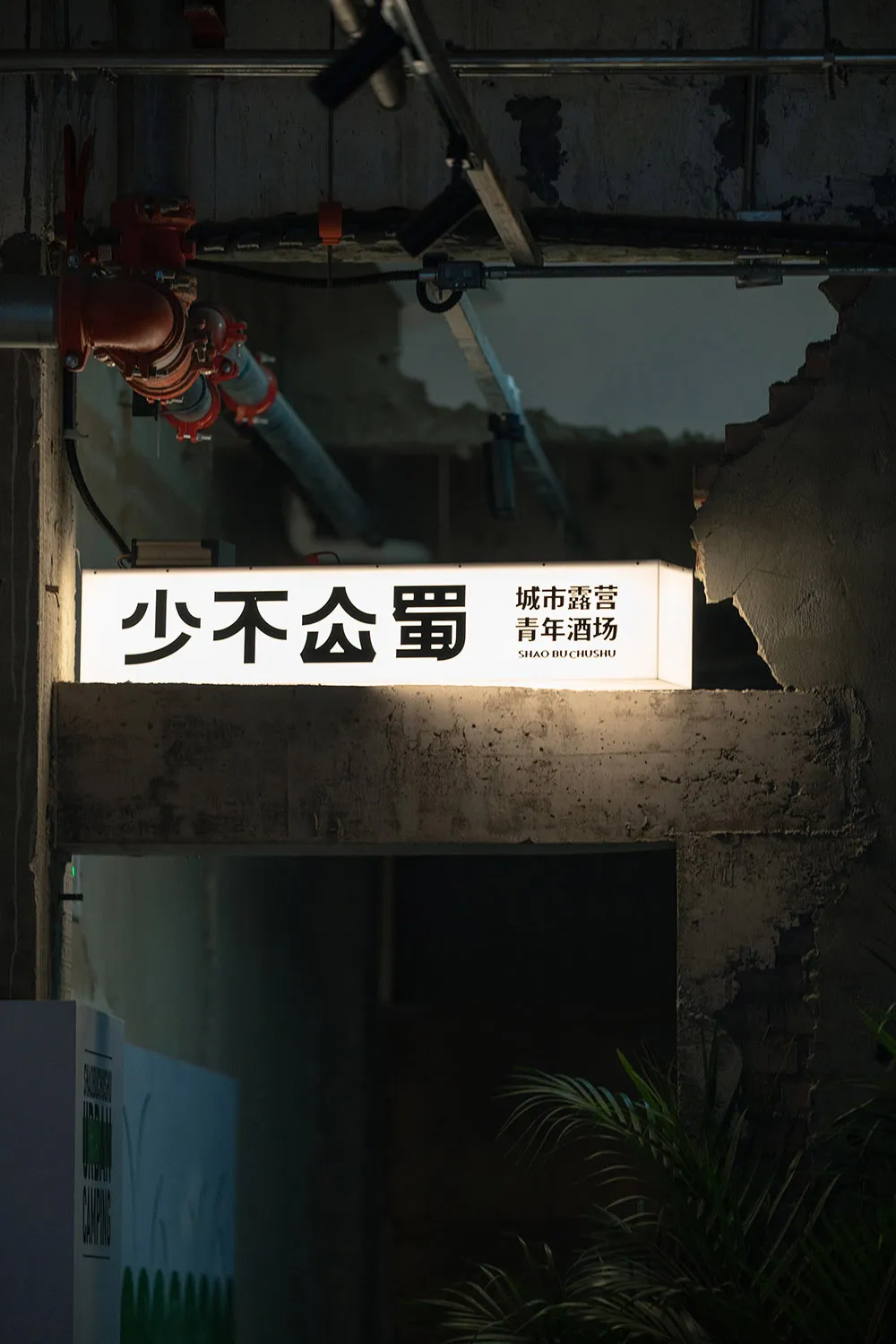 A minimalist signage with illuminated characters on a dark, industrial background.