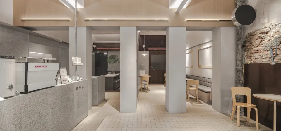 A modern, minimalist coffee shop interior featuring polished concrete, stone tiles, and wooden accents.
