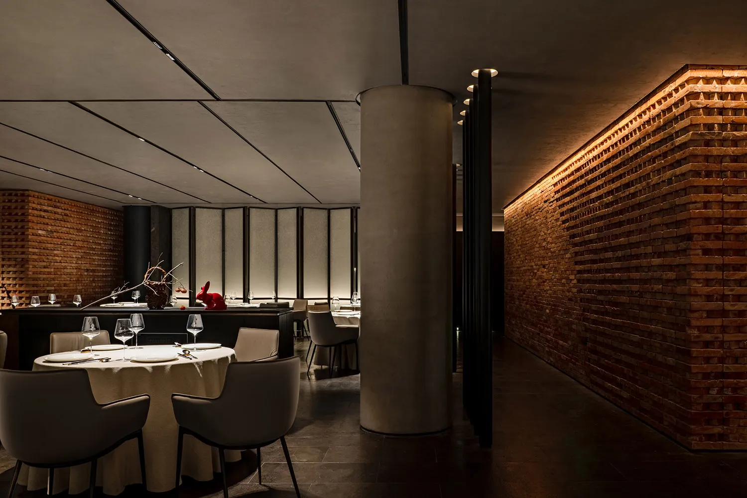Modern restaurant with brick and concrete interior, featuring round tables, chairs, and minimalist decor.