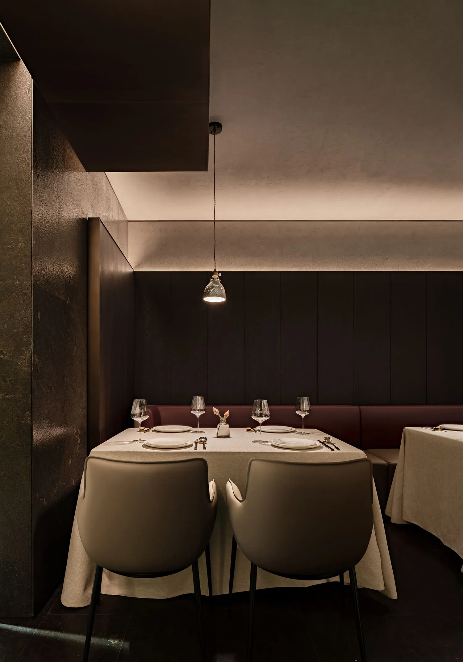 A modern restaurant dining table setting featuring a minimalist design with a fabric-covered table and upholstered chairs.