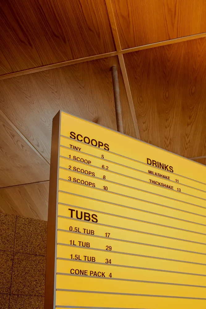 Yellow cardboard menu board with scoops and drinks prices.