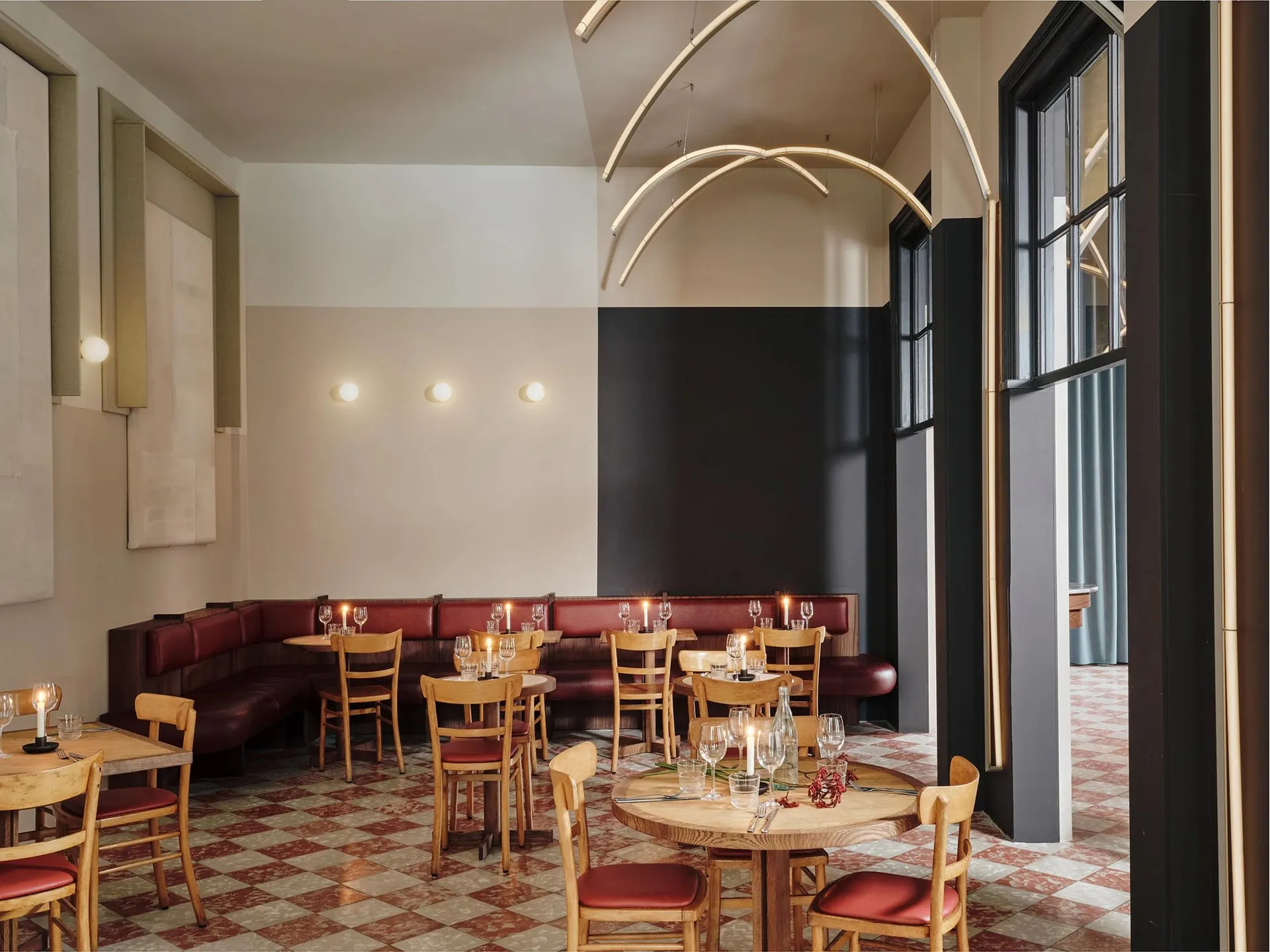 A modern cafe interior with sleek wooden tables, comfortable leather seating, textured plaster walls, and stylish glass chand