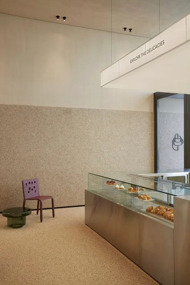現代麵包店內裝,玻璃展示櫃內擺滿各式糕點,搭配大理石吧台。