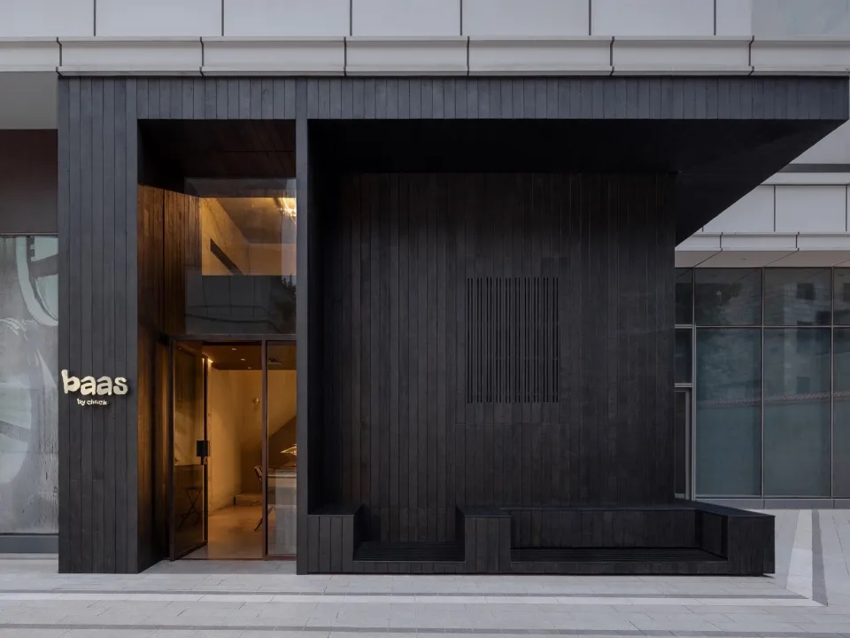 Modern storefront featuring dark wood panels and glass windows.