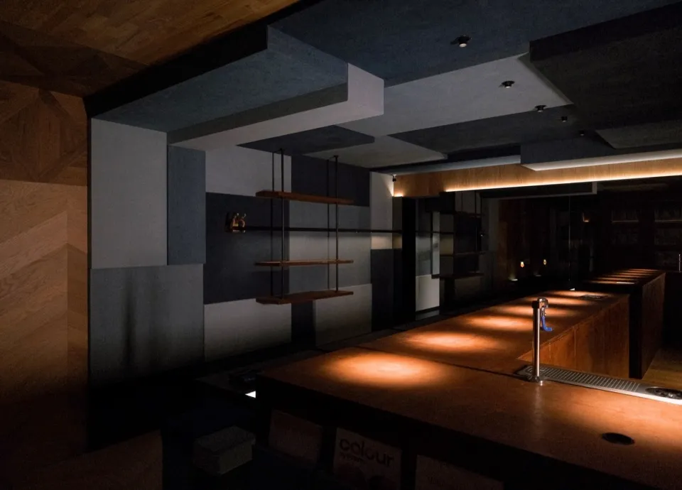Modern minimalist bar with wooden surfaces, featuring ambient lighting and sleek design.