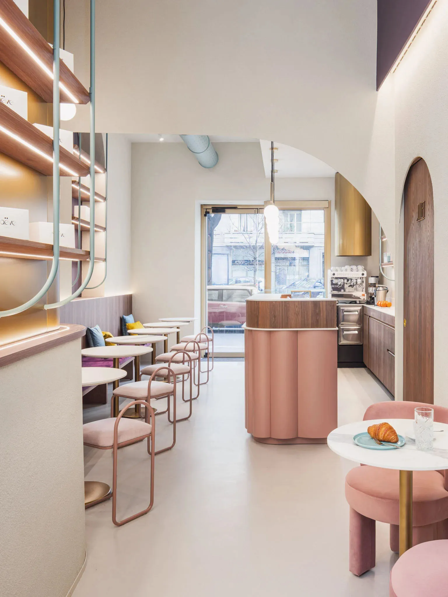 Pastel-colored cafe interior with round tables, chairs, and bar area.