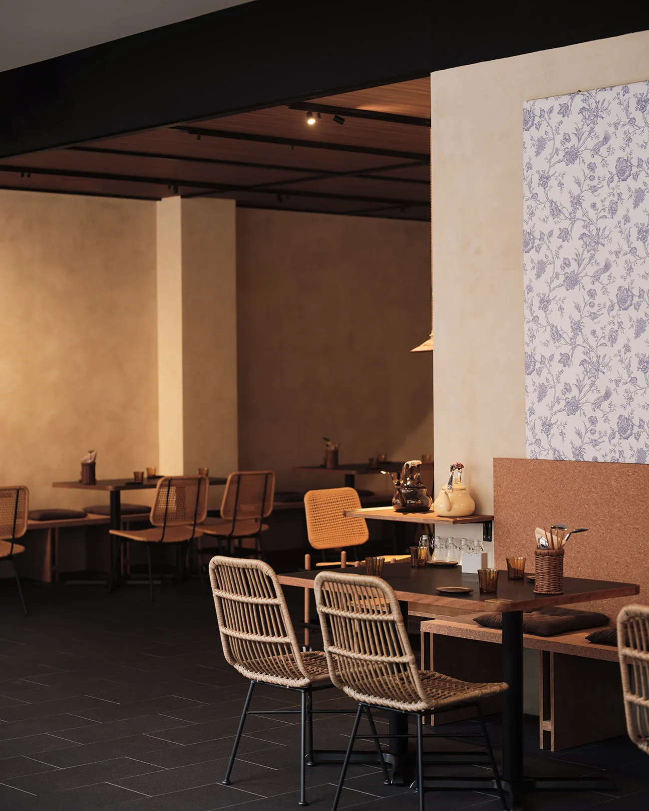 Modern cafe interior with wooden tables, woven chairs, and floral wallpaper