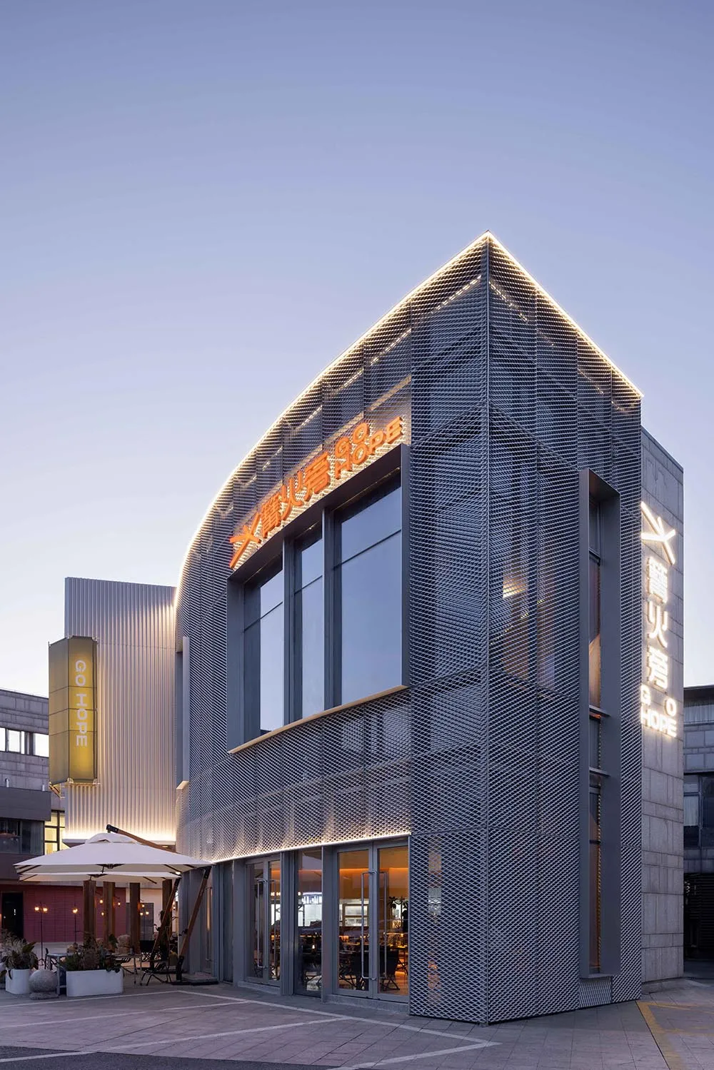 Modern commercial retail storefront with metal netting cladding and illuminated signage