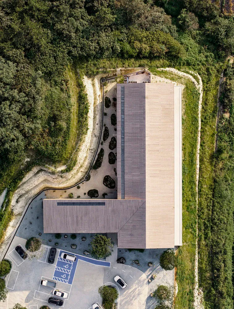 Aerial view of a modern office with a wooden exterior and a stone path leading to a parking area.