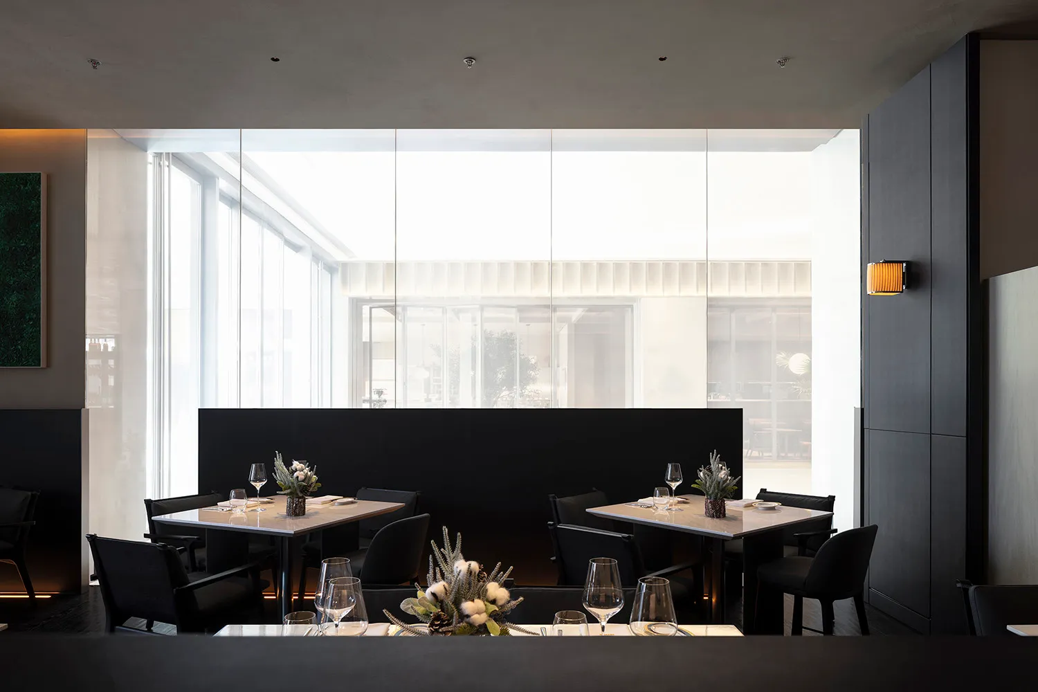 A modern restaurant interior featuring black metal and marble tables, chairs, and accents.