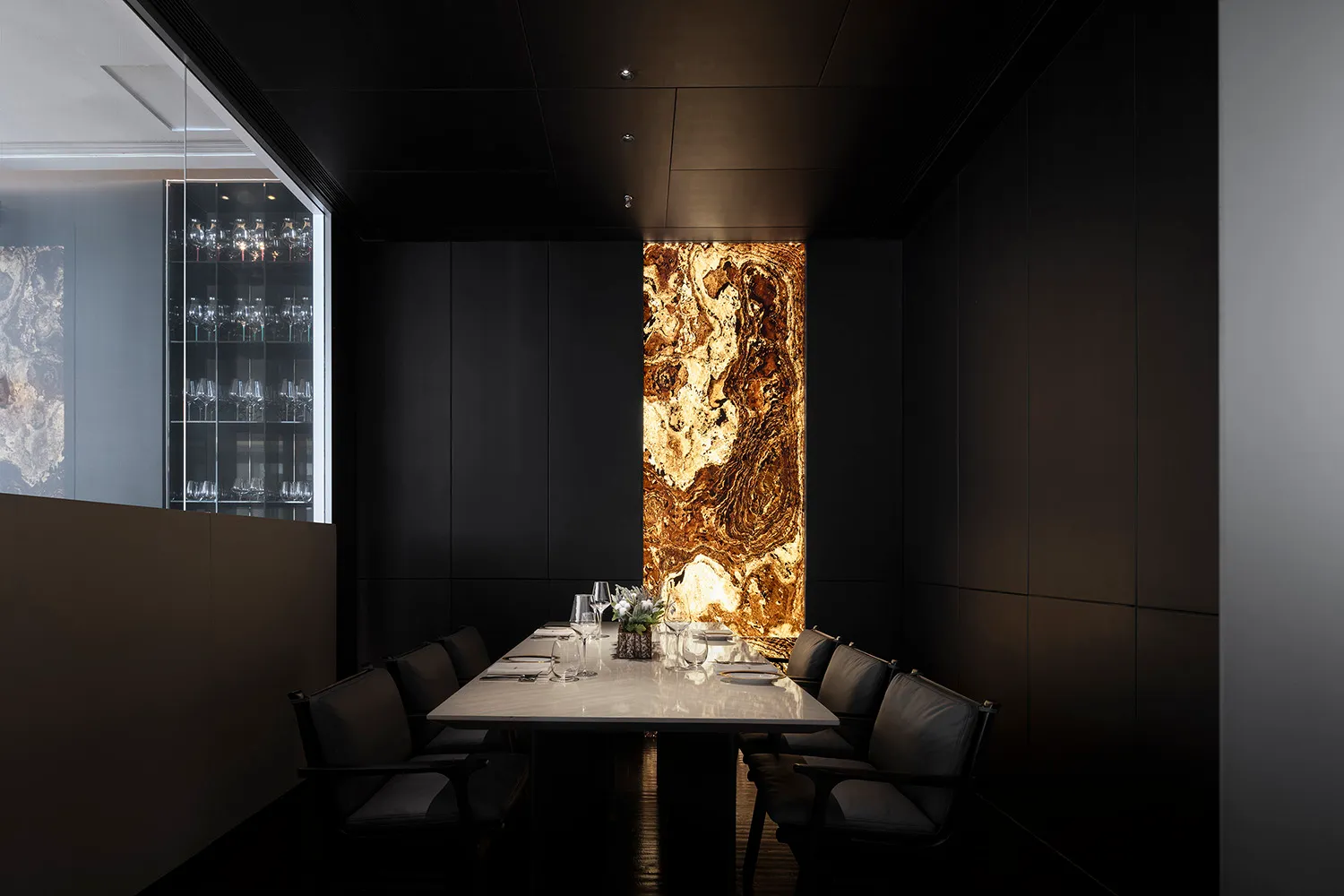 A modern private dining room with a sleek, minimalist design featuring a long table made of polished marble, surrounded by co