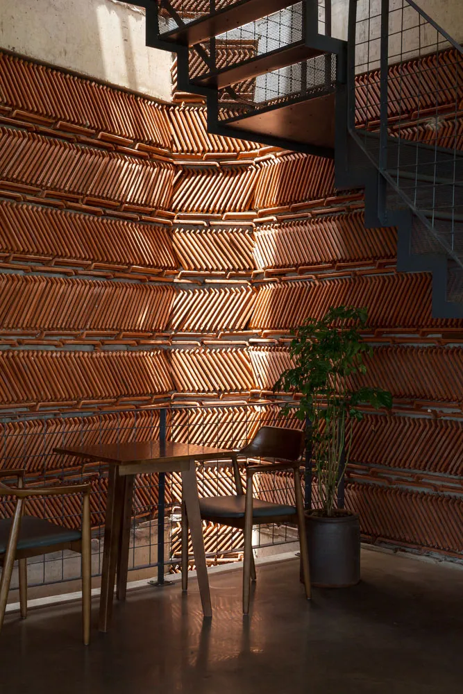 A cozy wooden coffee shop interior with a modern design, featuring a wooden table and chairs, a green plant, and a geometric