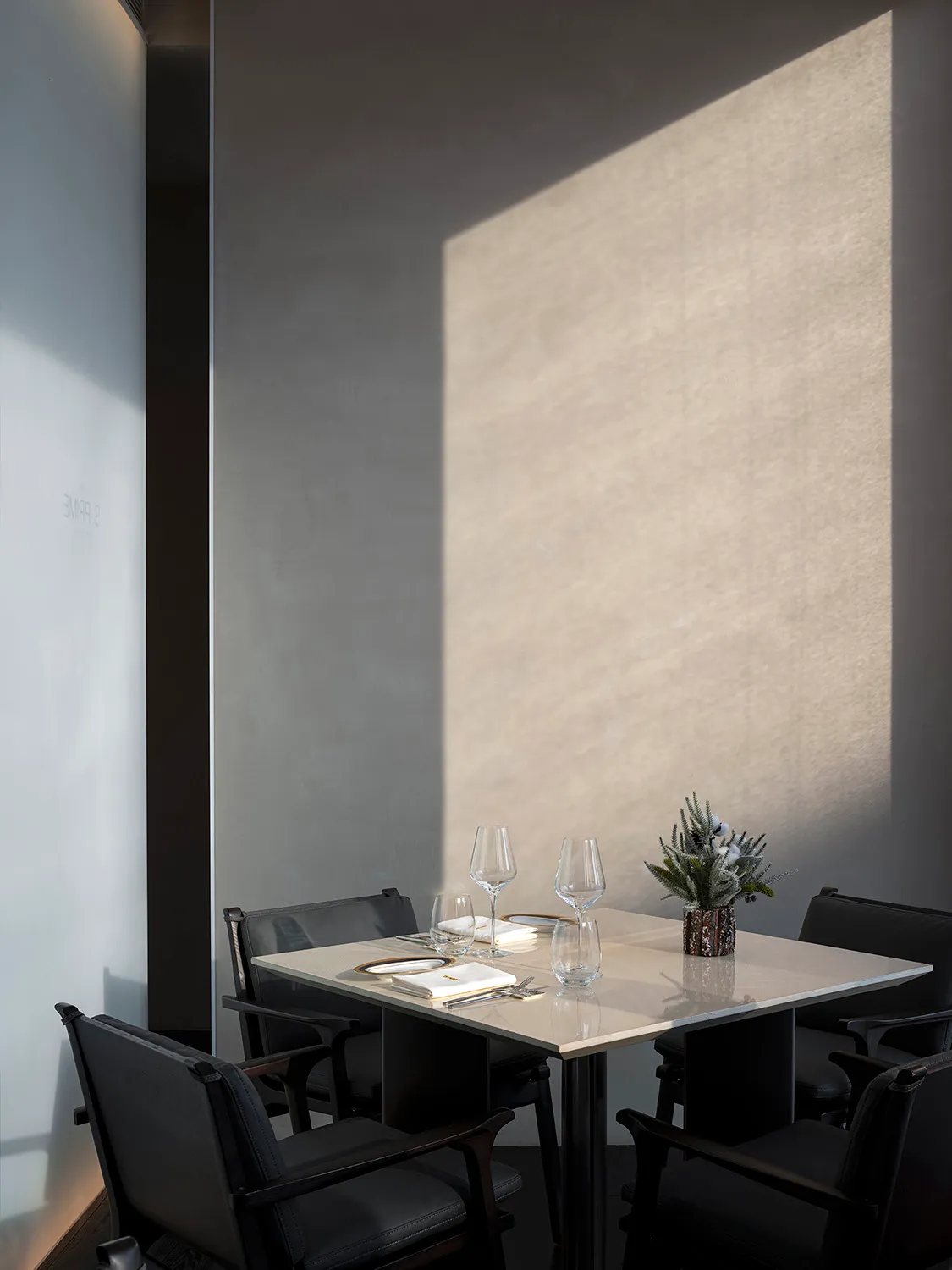 A minimalist restaurant interior with concrete and steel materials and elegant table setting.