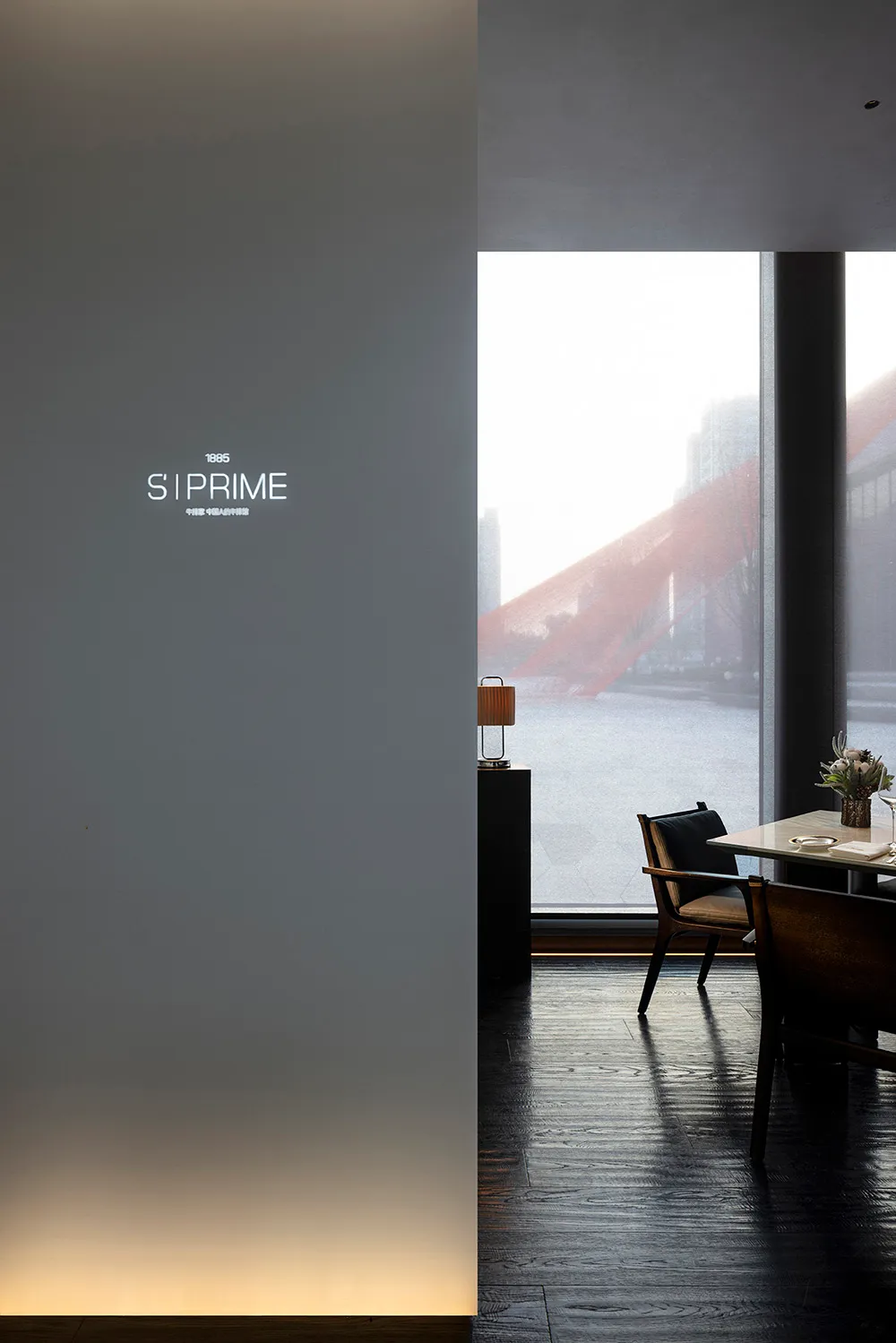 Modern, minimalist restaurant interior with large windows, wooden floors, and contemporary furniture.