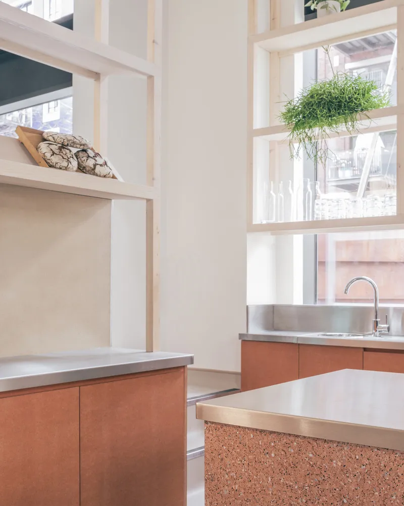 A minimalist kitchen featuring metal countertops and red terrazzo floor tiles.