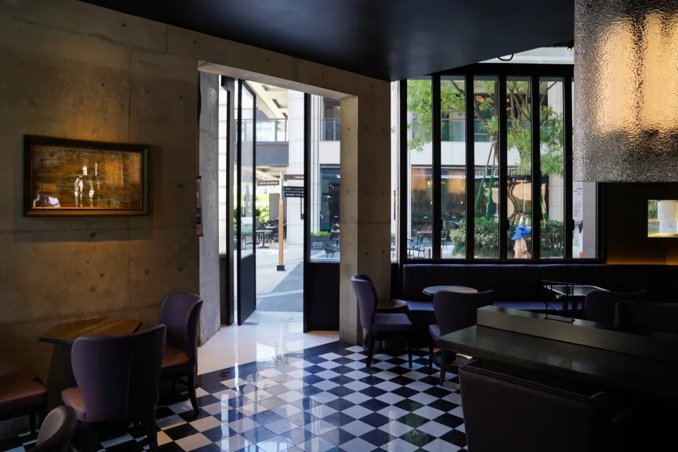 Modern interior of a restaurant with concrete walls, glass walls, and leather furniture.