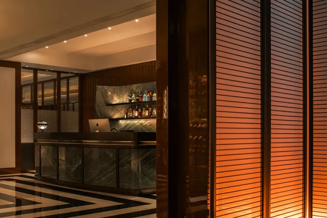 Interior design of a modern bar featuring a marble and concrete counter with glass elements.