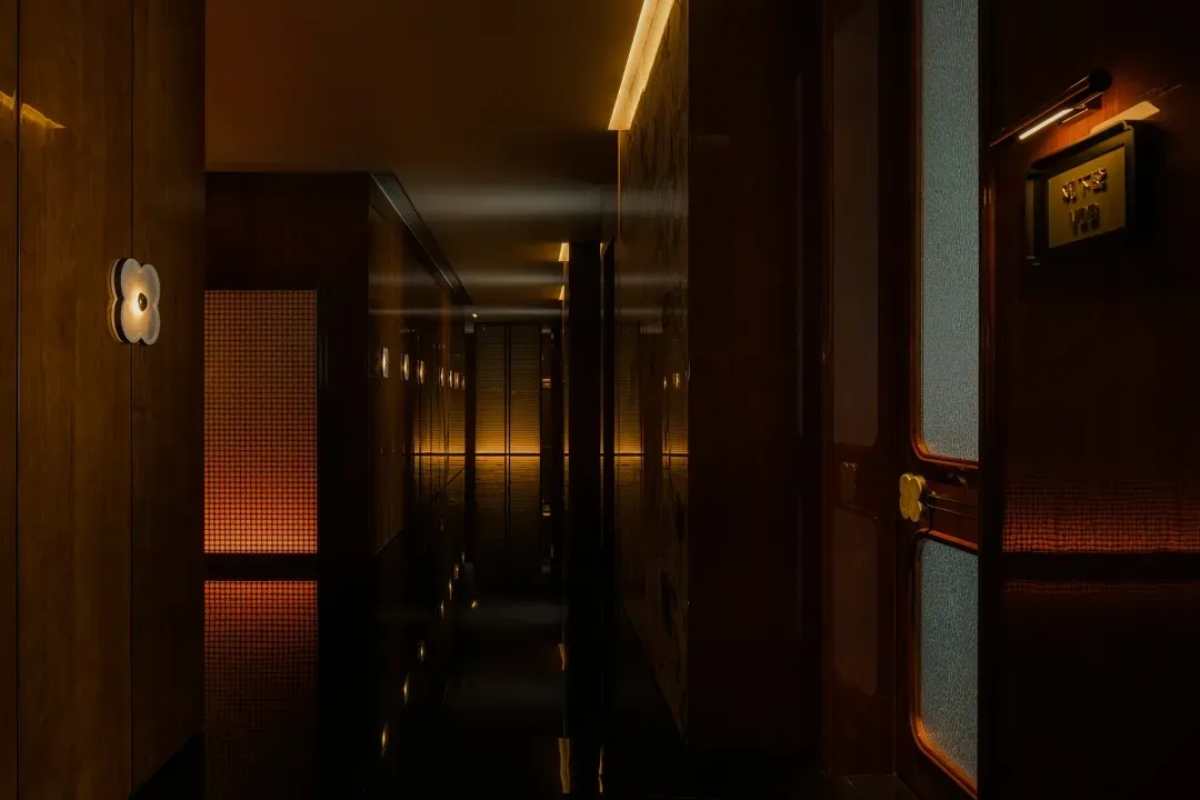 A minimalist hotel corridor with wooden walls and warm lighting, showcasing modern design elements.