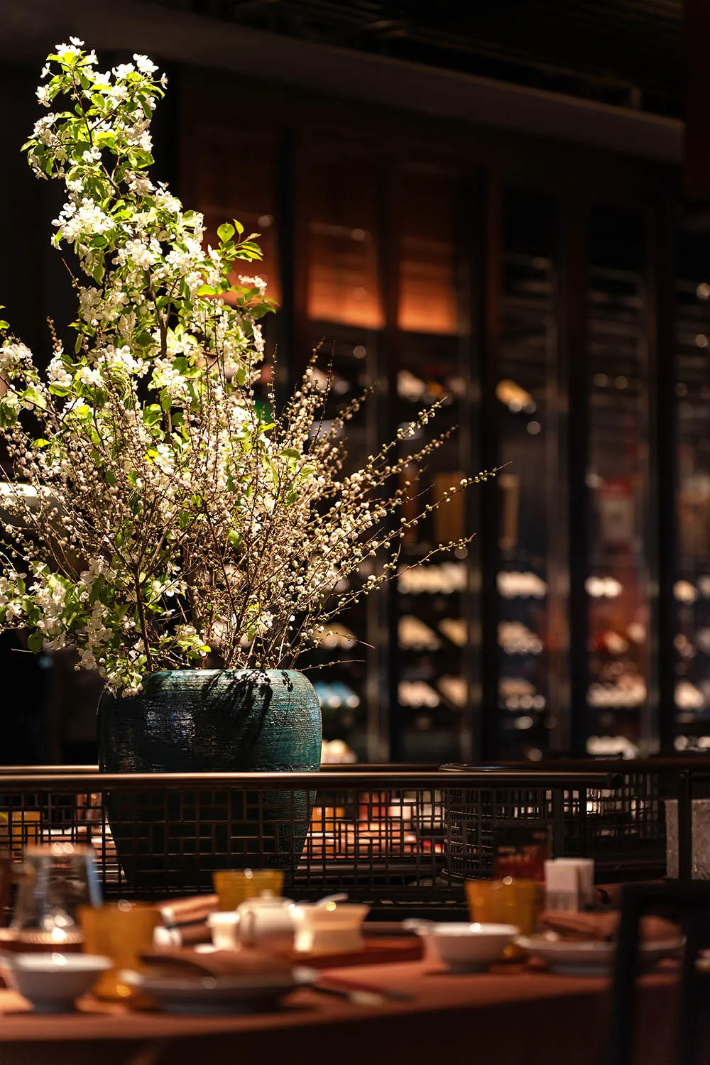 Floral arrangement in a ceramic vase on a table in a restaurant setting.
