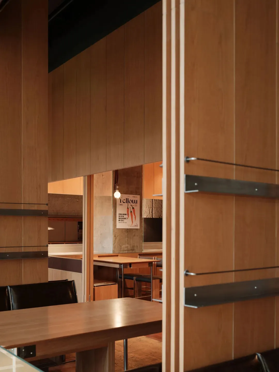 A minimalist restaurant seating area with wooden tables and chairs.