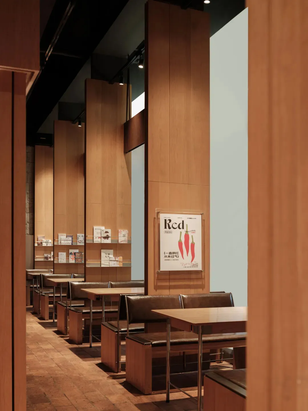 A detailed view of a modern restaurant dining room with cork floor, wood-paneled walls, and bookshelves filled with books.