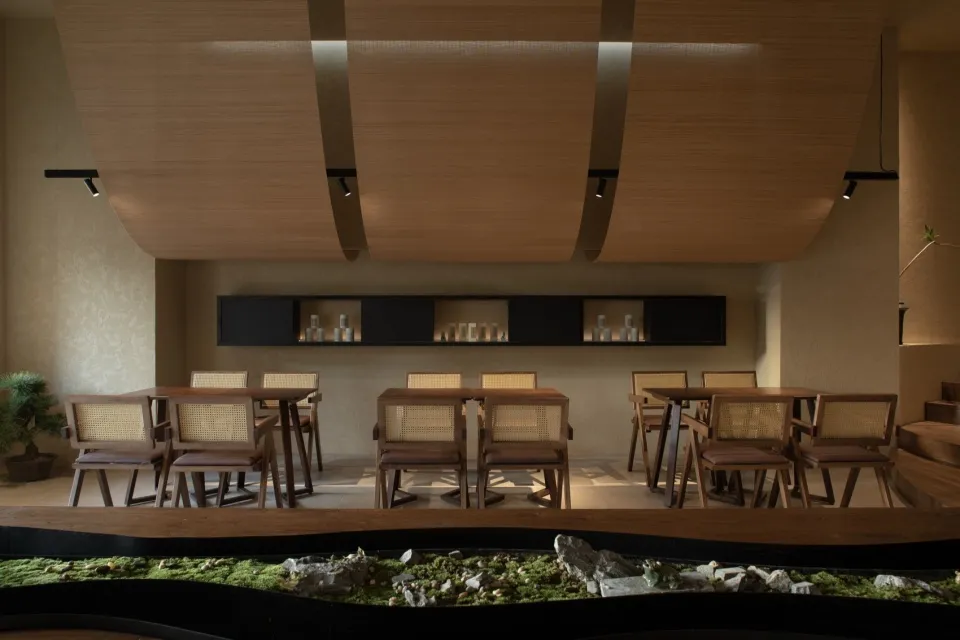 A modern restaurant interior designed with wooden elements and a tranquil greenery feature.