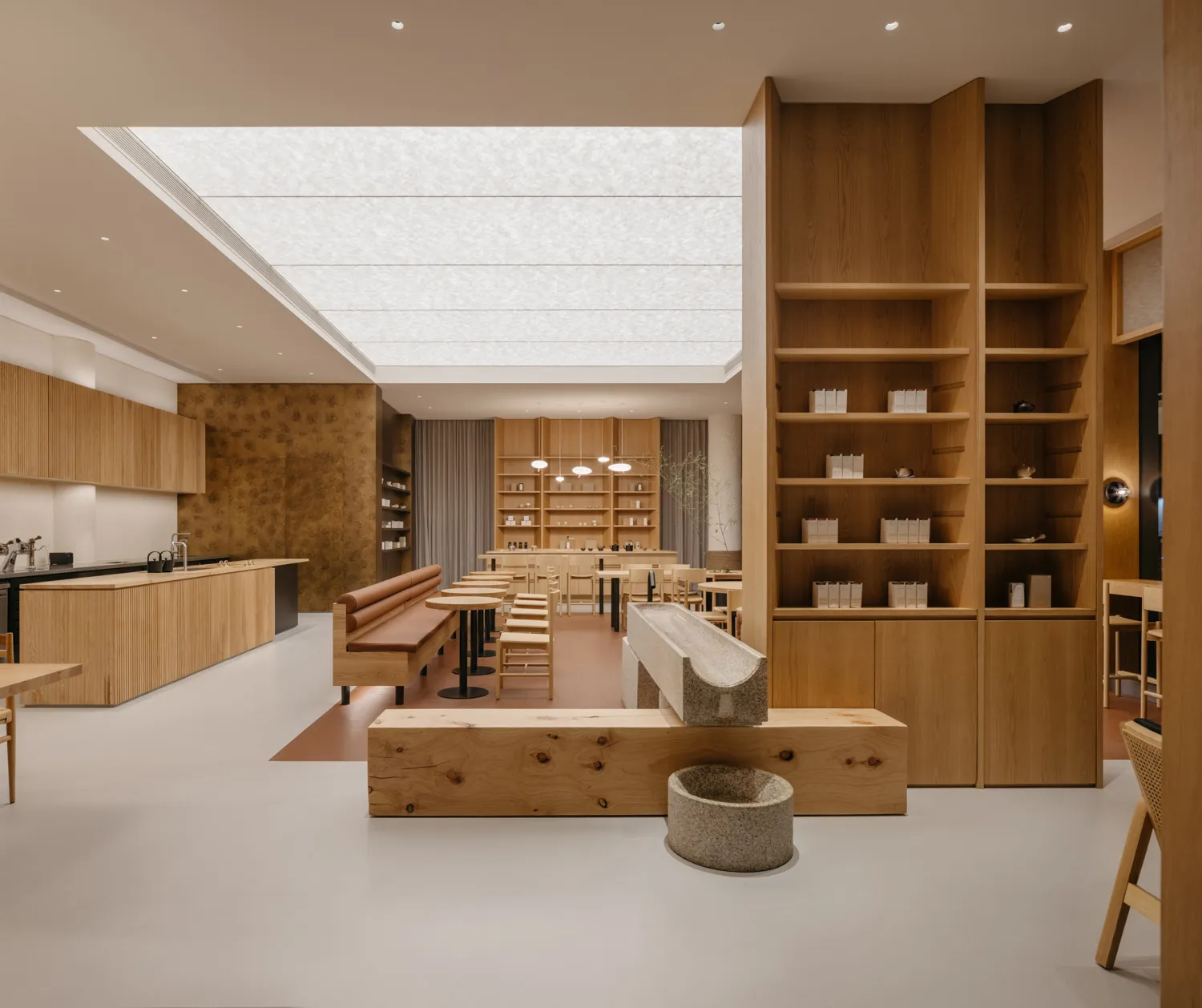 A minimalist coffee shop interior featuring extensive wood decor and a central skylight.