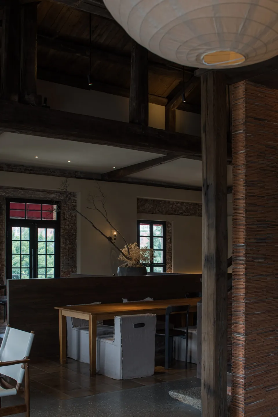 A rustic, industrial-style restaurant interior with exposed wooden beams, brick walls, and a cozy seating area.