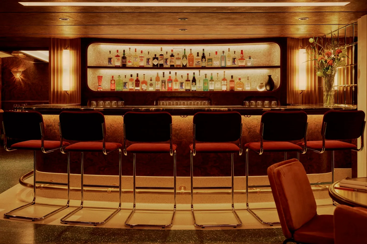 A modern bar with a marble countertop and stools.