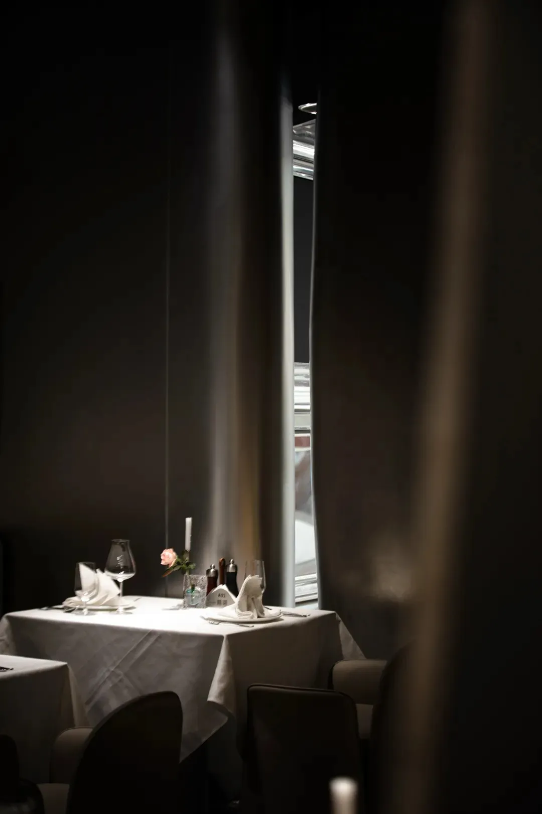 Modern restaurant interior with white cloth table setting and single rose centerpiece.