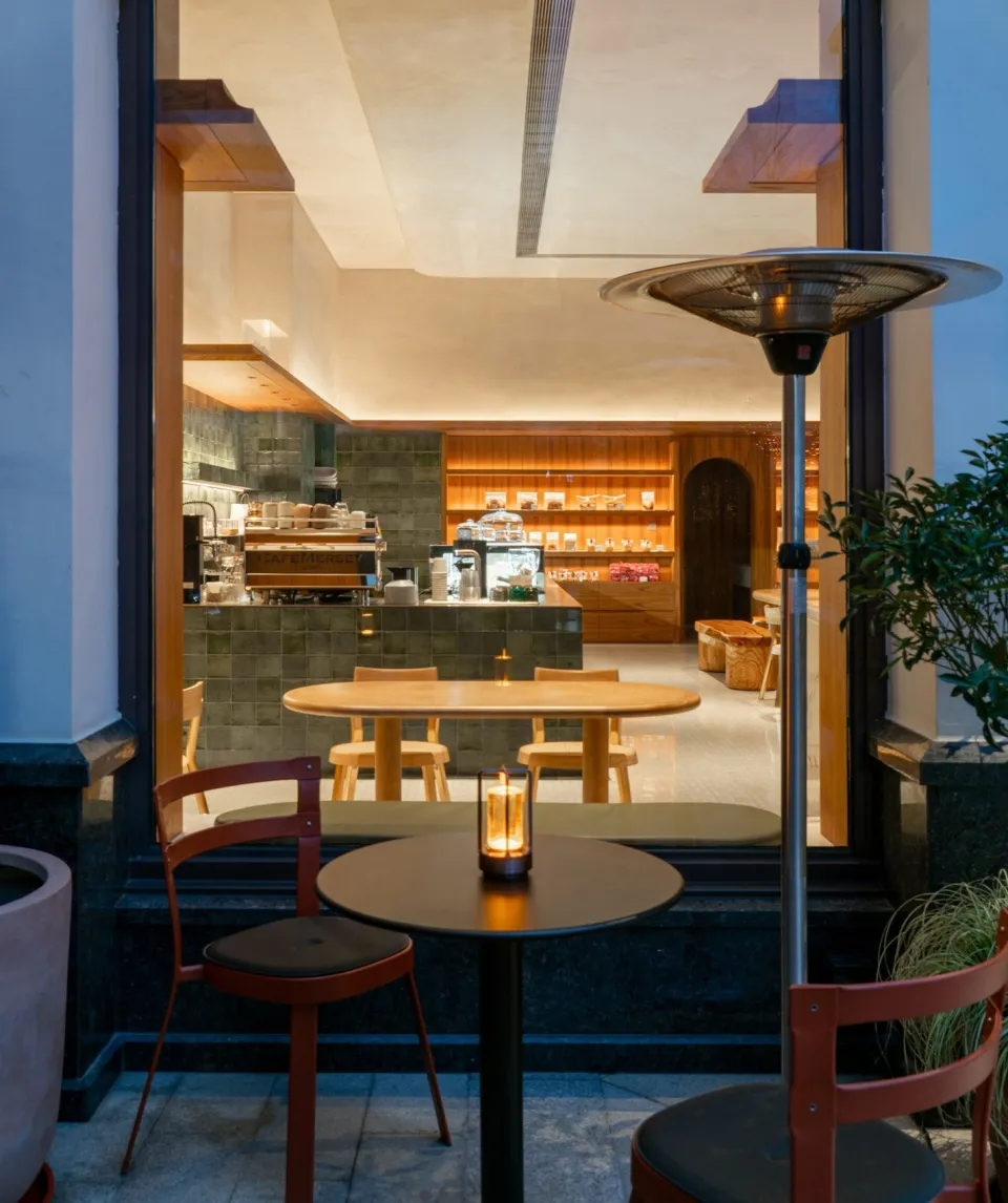 A cafe interior featuring wooden tables and chairs with a concrete floor.