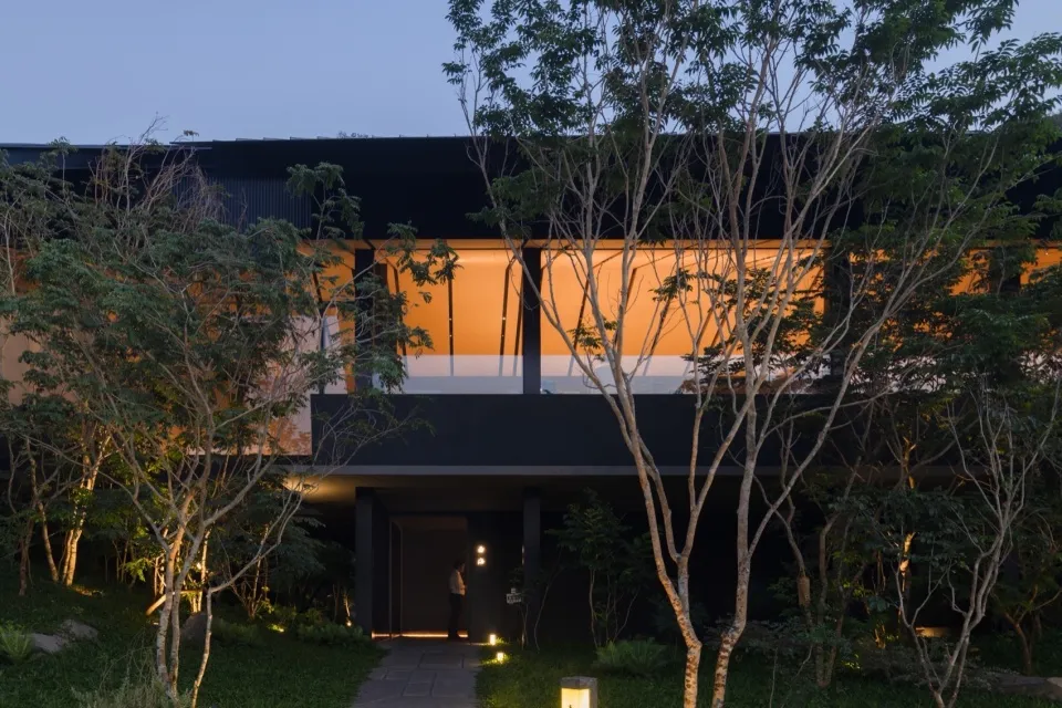 A minimalist house facade featuring a combination of wood, glass, and metal materials.