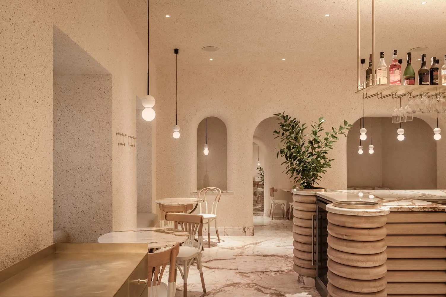 Interior view of a modern restaurant with concrete walls, marble countertops, and wooden furnishings.