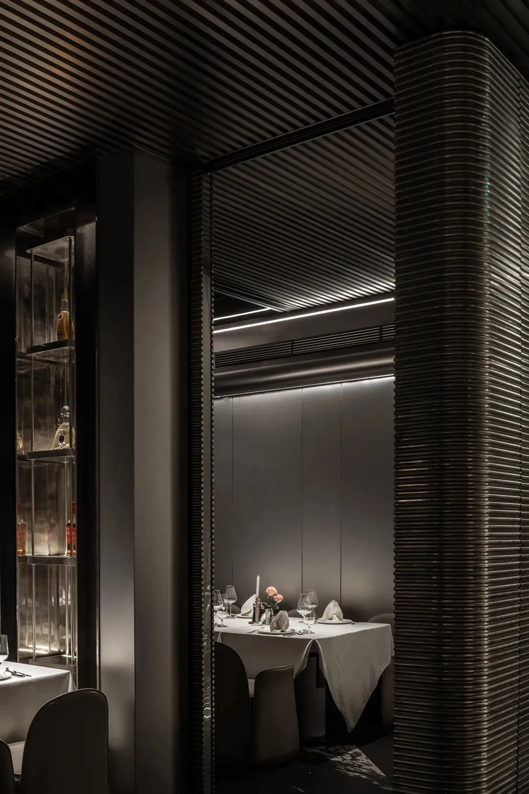 Modern restaurant dining room with metallic elements and white tablecloth.