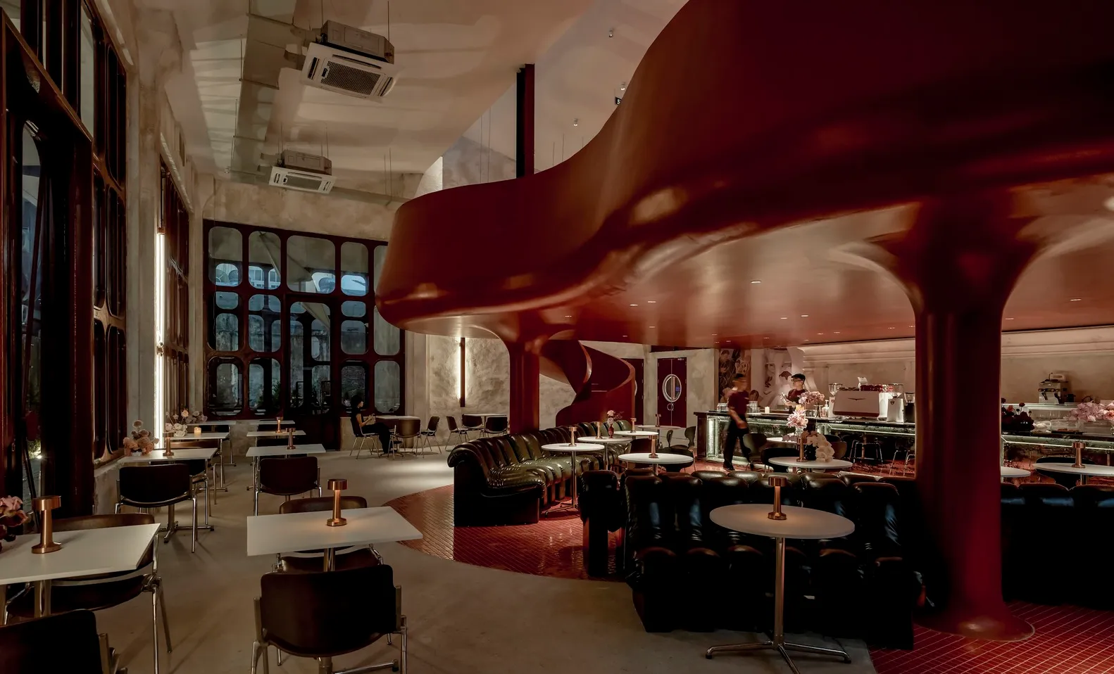 A modern architecturally styled cafe with red and black interior decor, featuring metallic and glass elements.