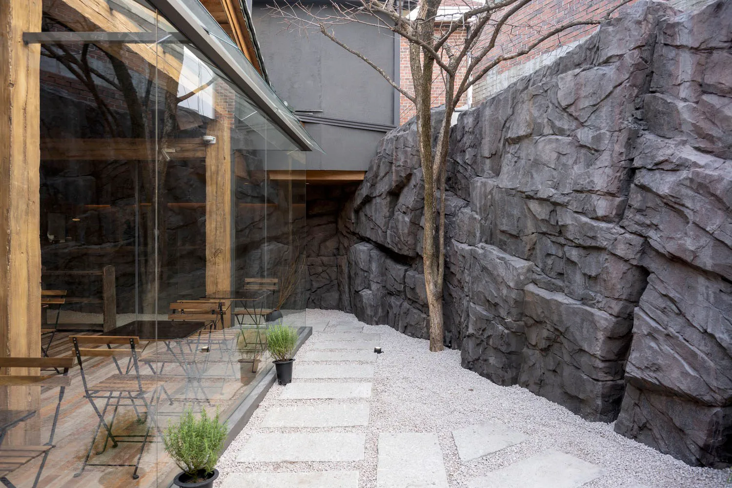 A modern coffee shop entrance featuring concrete walls, lighting, and seating.