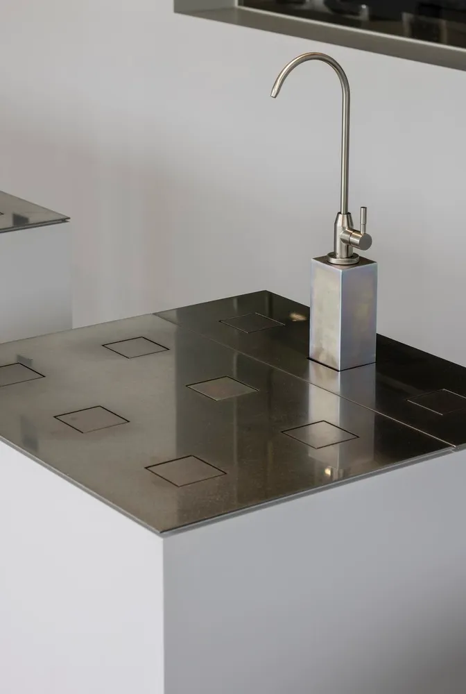 Modern kitchen featuring a metal countertop with integrated sink and faucet.