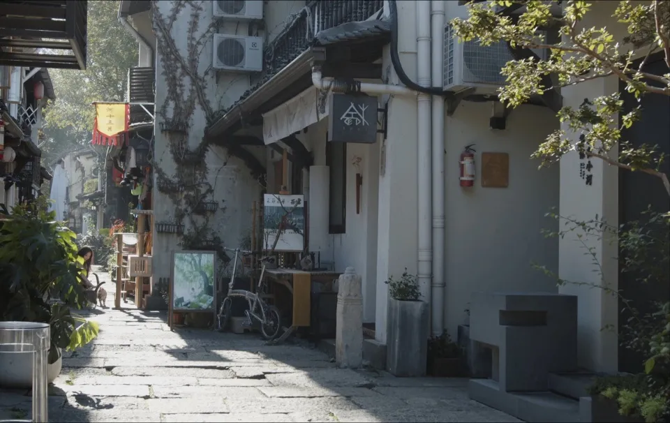 一條狹窄的石板街道,兩旁林立商店與建築,融合現代與傳統建築元素。