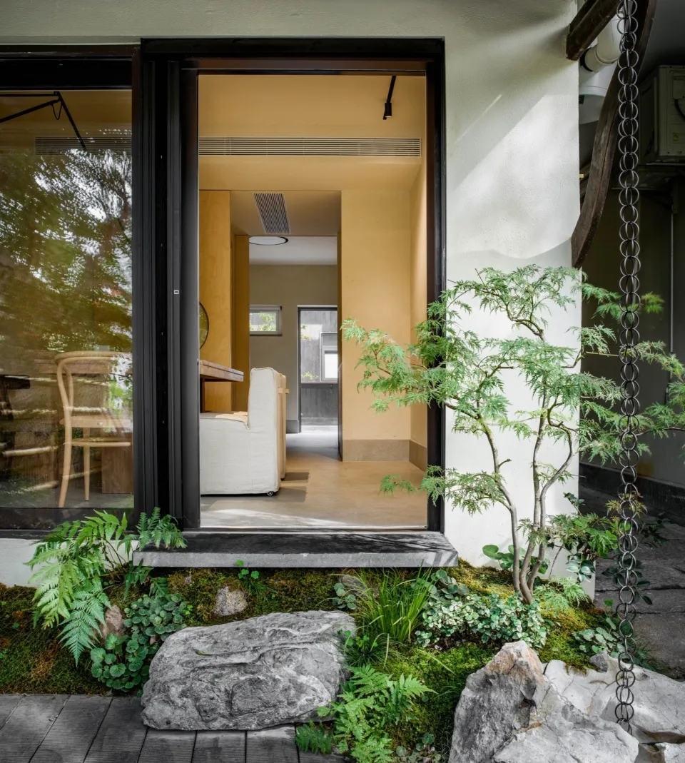 Modern living room with wooden furniture, stone walls, and green plants.