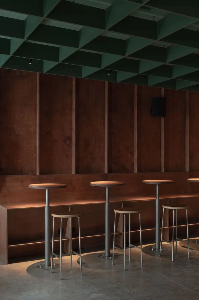 High-top bar tables and stools in a wooden restaurant interior with exposed ceiling beams