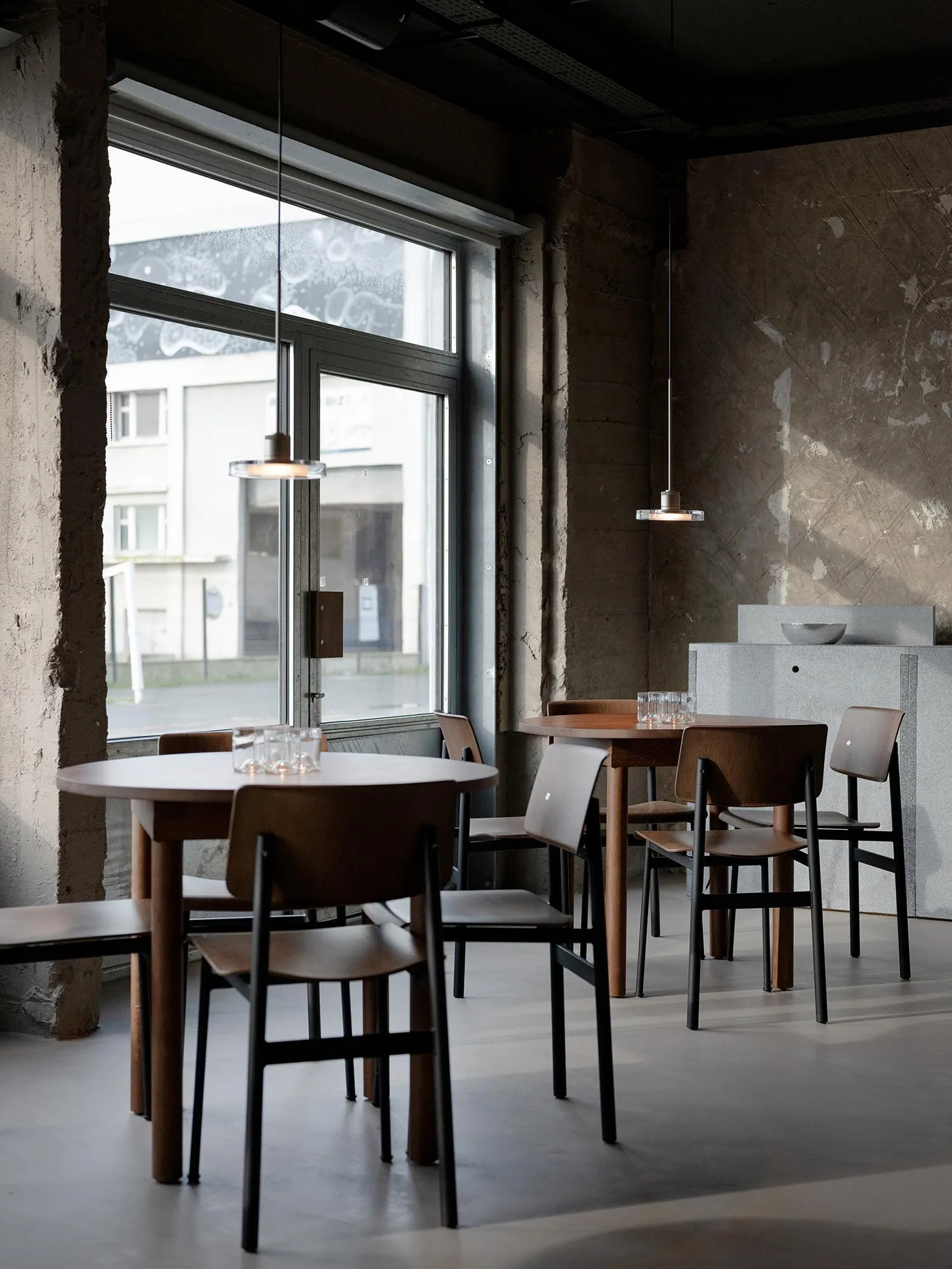 Industrial-style restaurant interior with concrete walls and timber furniture.