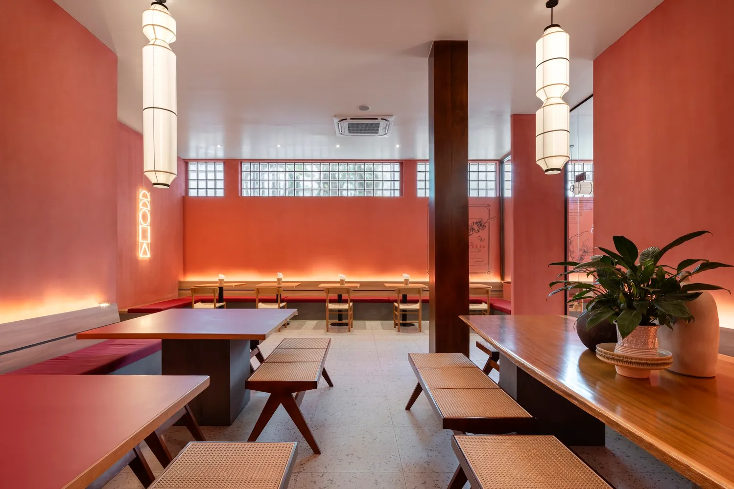 Cafe interior with wooden furniture, red walls, and modern lighting.
