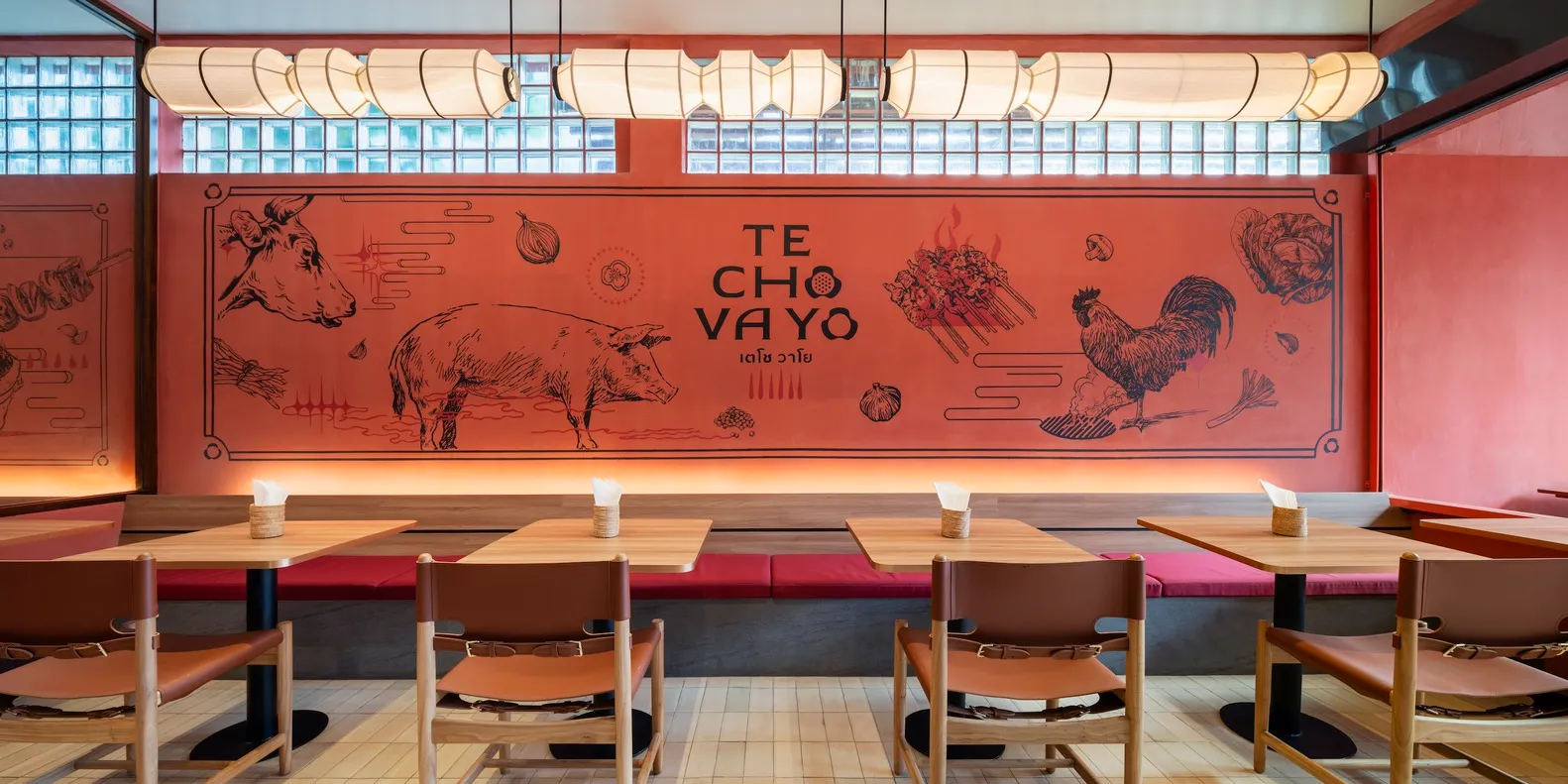 A modern restaurant interior with wooden tables, leather chairs, and a large mural depicting various cooking elements and tex