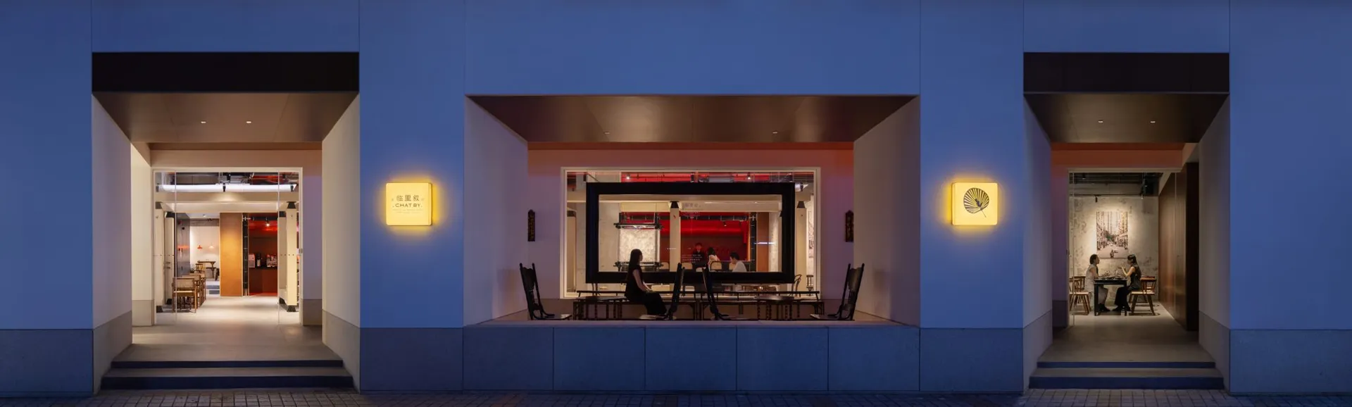 An exterior view of a coffee shop illuminated by luminous materials.