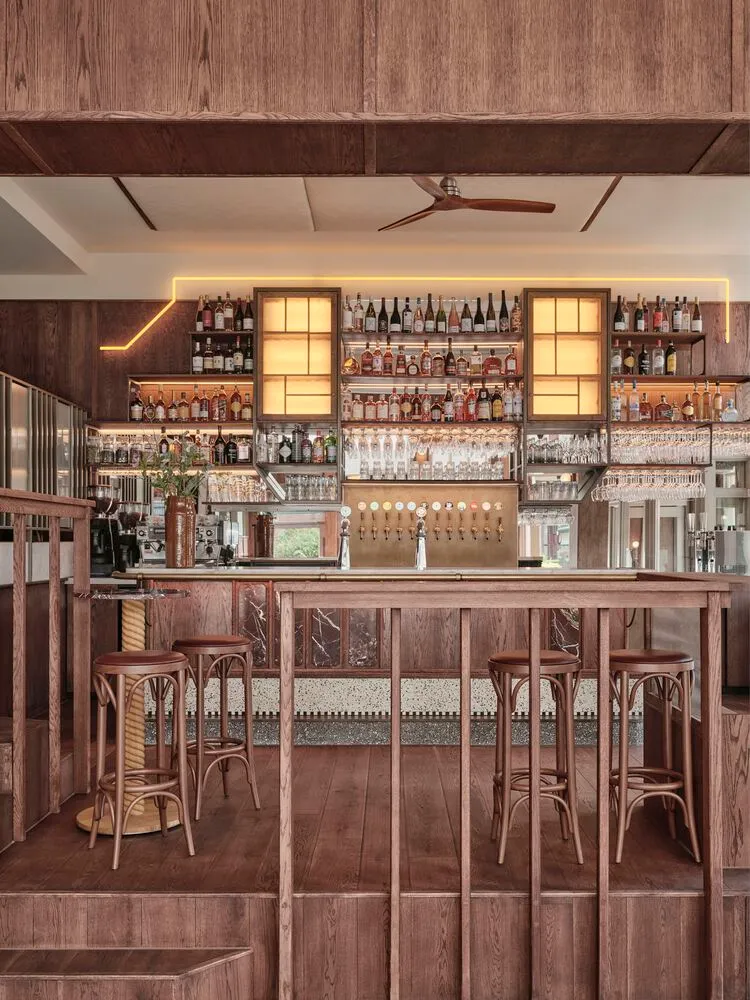 Modern interior of a cafe-bar with wooden flooring, marble accents, and metal details.