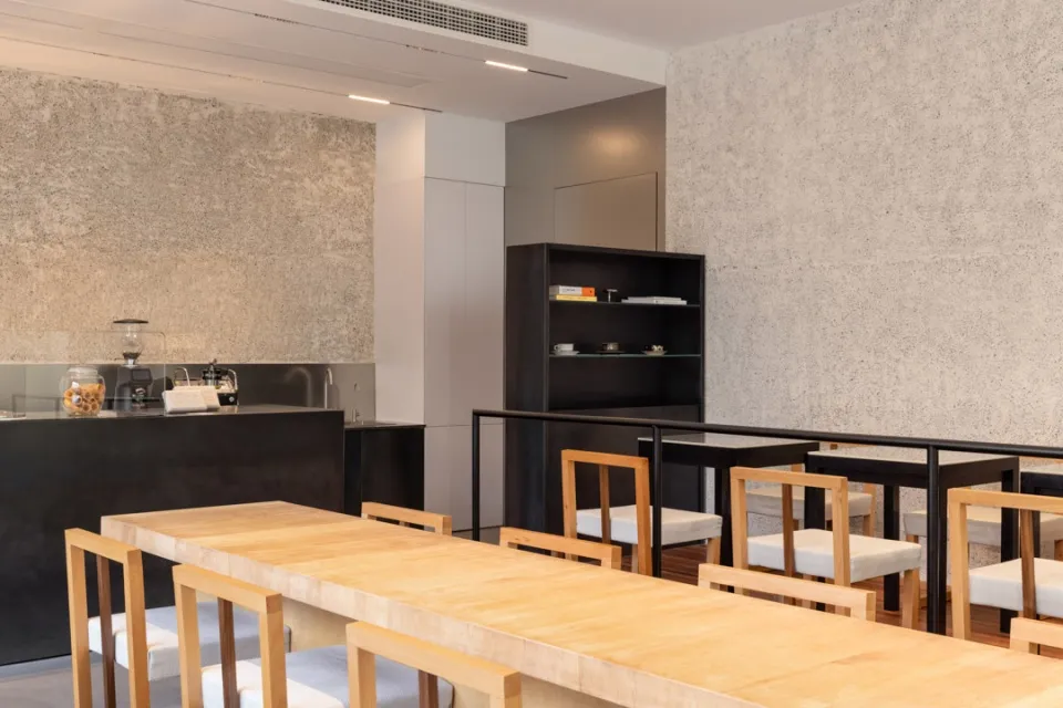 Interior design of a modern cafe featuring wooden tables, concrete walls, and metal railings.