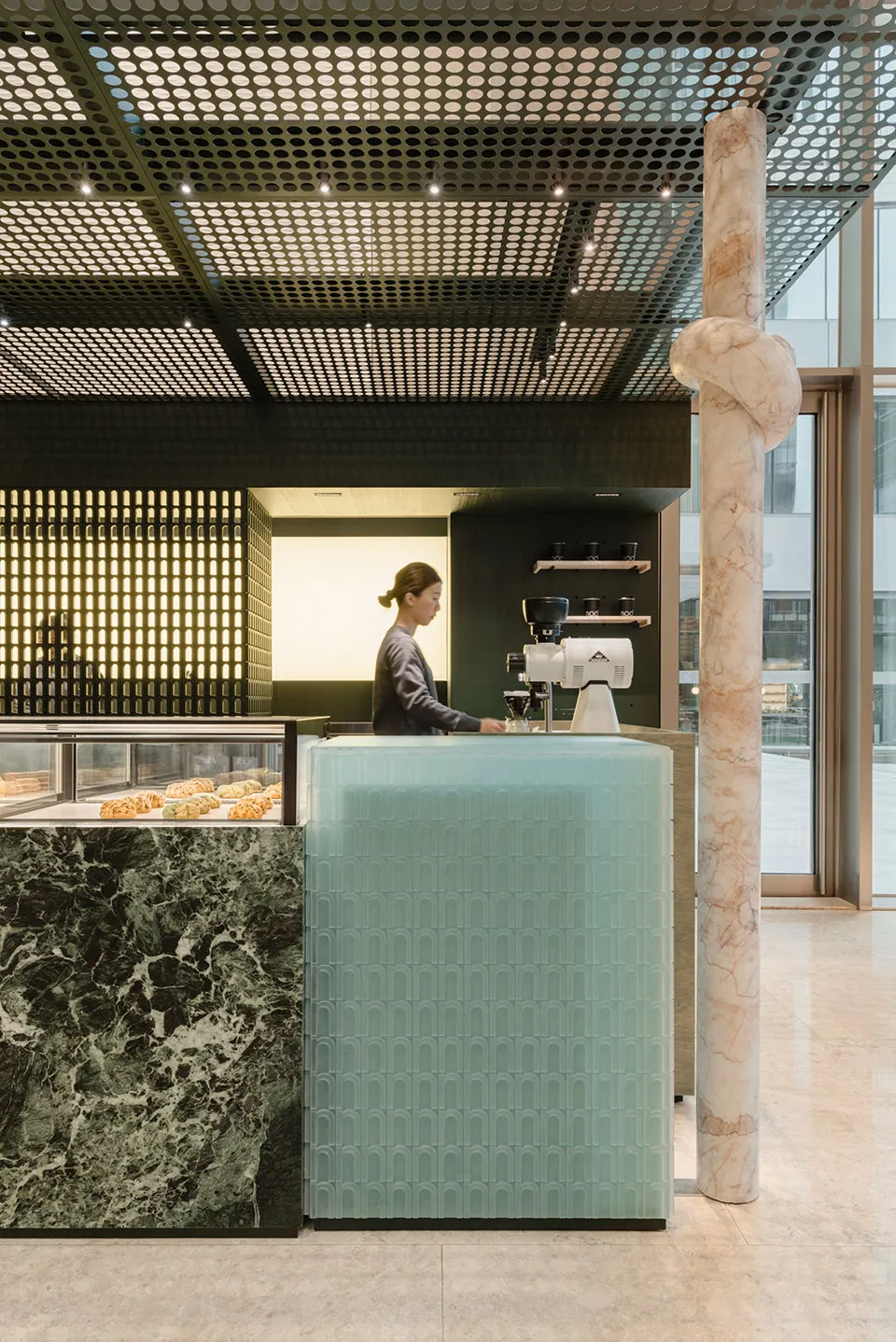 A minimalist coffee shop interior featuring a glass counter with a marble column.